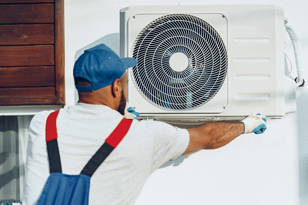 HVAC technician servicing a wall-mounted mini-split AC unit in Royal Oak MI