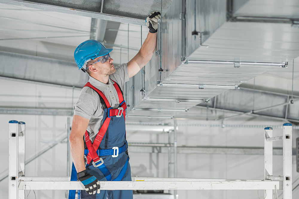 HVAC technician inspecting commercial ductwork across Metro Detroit service areas