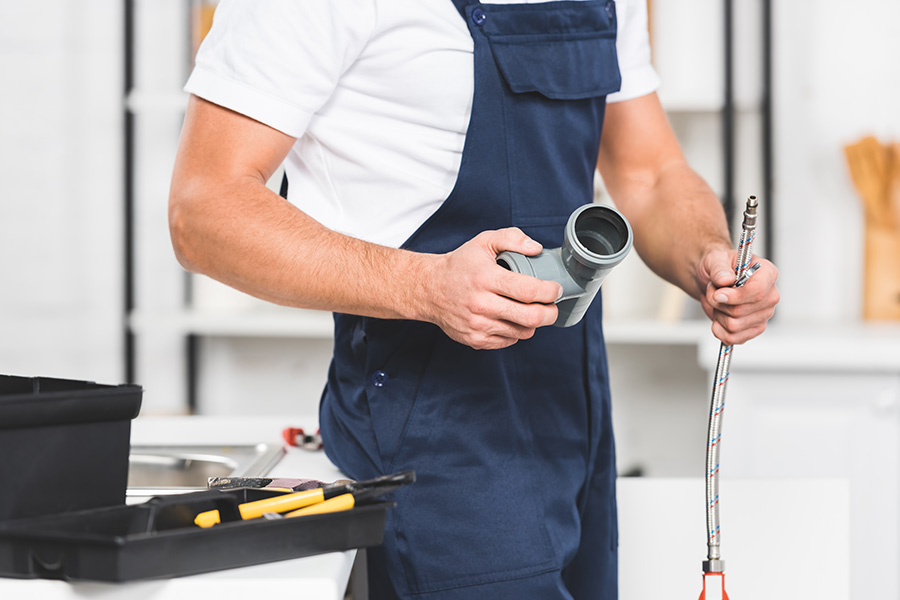 Airtech Mechanical plumber inspecting pipe fittings during leak detection in Livonia, MI