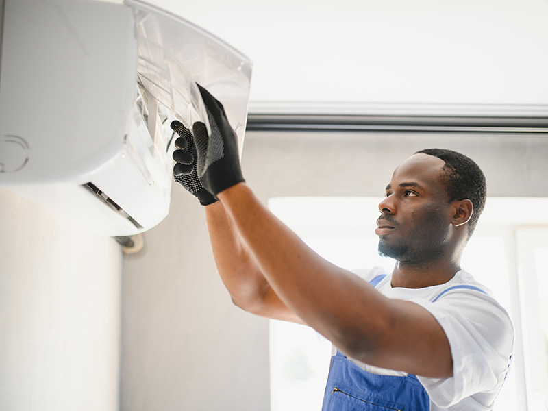 Certified technician servicing wall-mounted ductless mini-splits and inspecting the indoor air filter in Livonia, MI