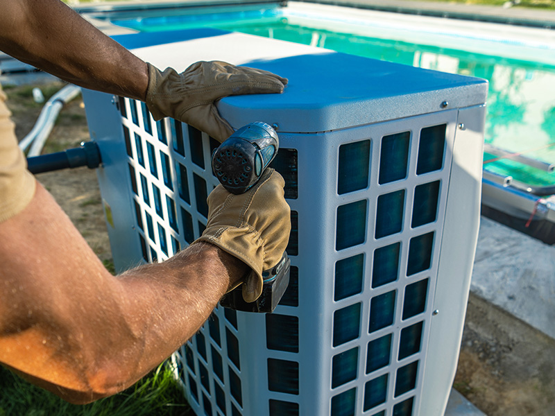 Airtech technician servicing outdoor pool heaters alongside a backyard swimming pool